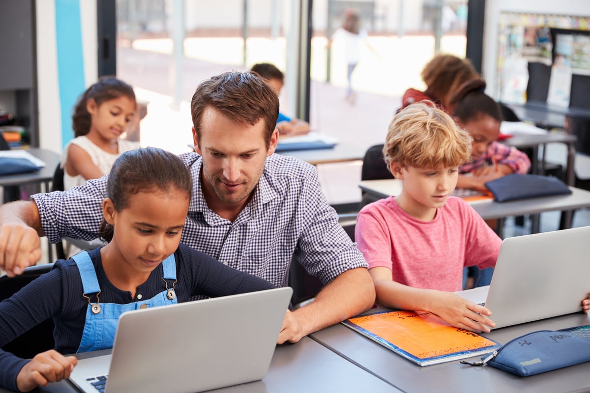 male-teacher-helping-student-on-laptop